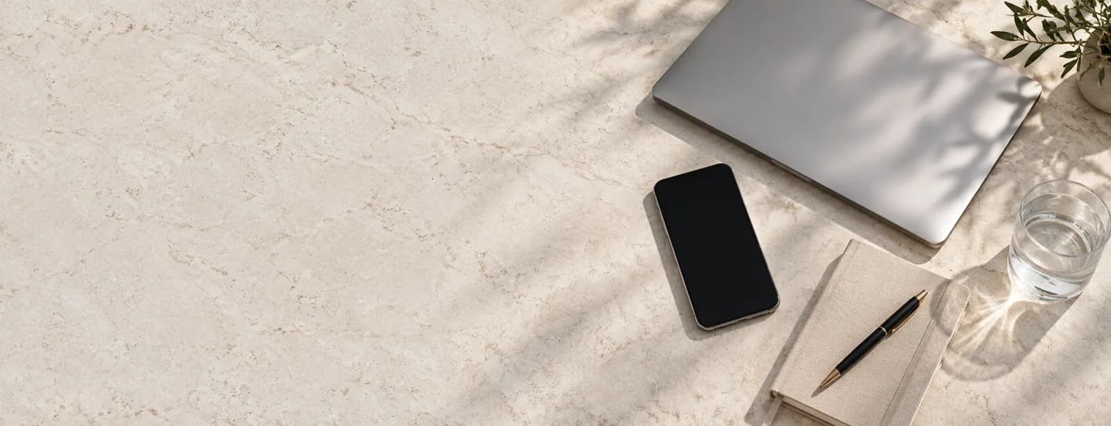 A phone, laptop and notebook on a stone desk